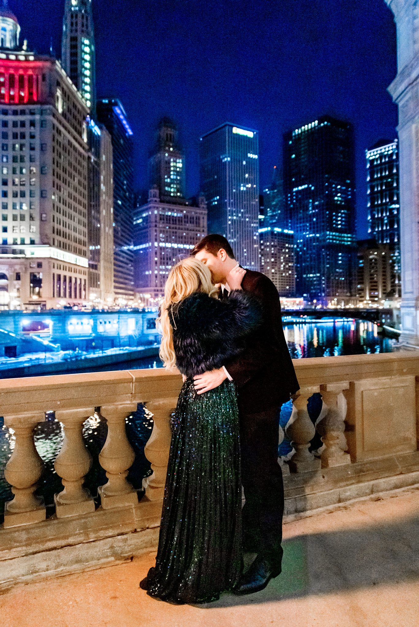 man and woman in suit and green sparkly dress kissing at night for Wrigley Building engagement pictures