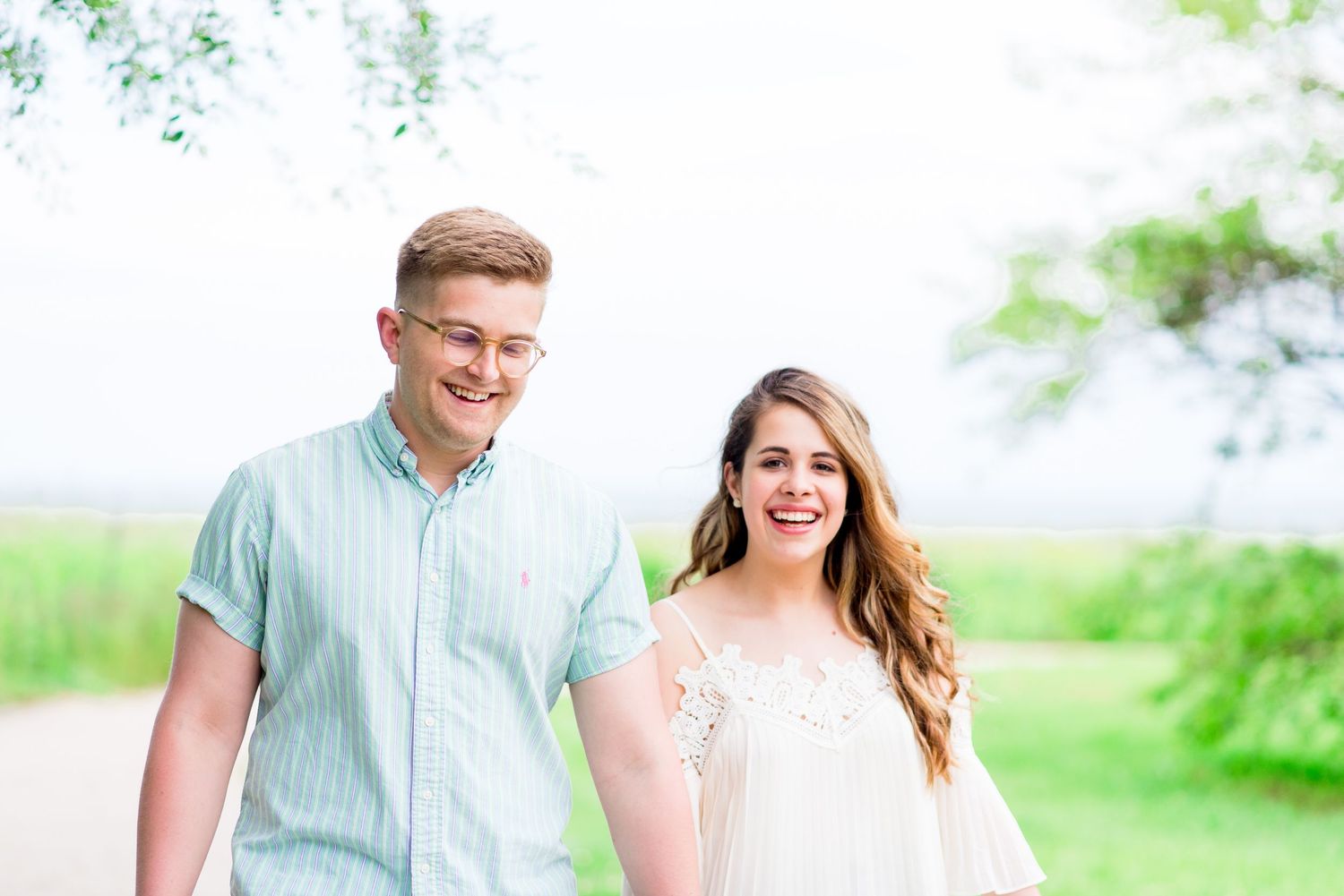 young engaged couple holding hands and walking along Montrose Harbor trail for their Chicago sunrise engagement pictures