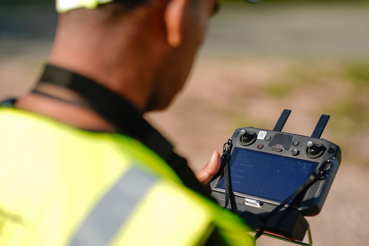 Operator using a remote control interface for drone navigation in bright daylight.