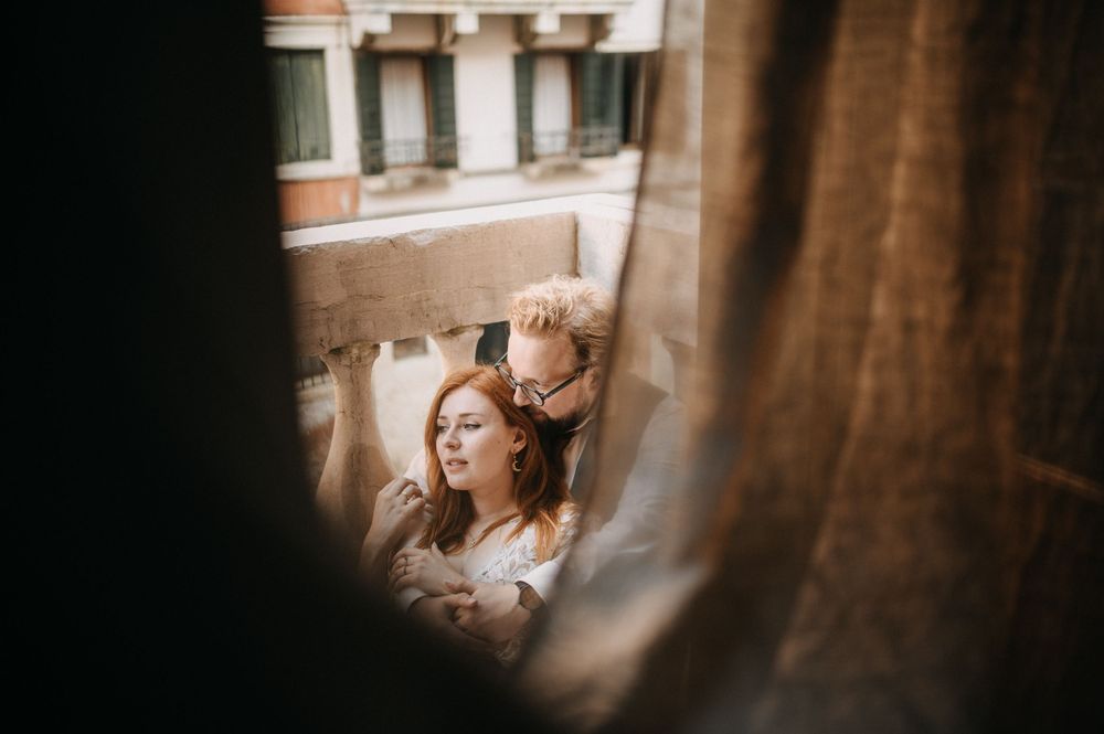 A candid wedding moment captured through an open window with warm natural light.