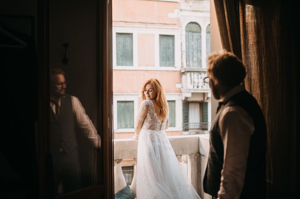 A sunlit wedding scene through a window frame in Venice.