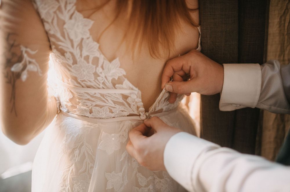 Close-up details of lace wedding dress with soft window lighting.