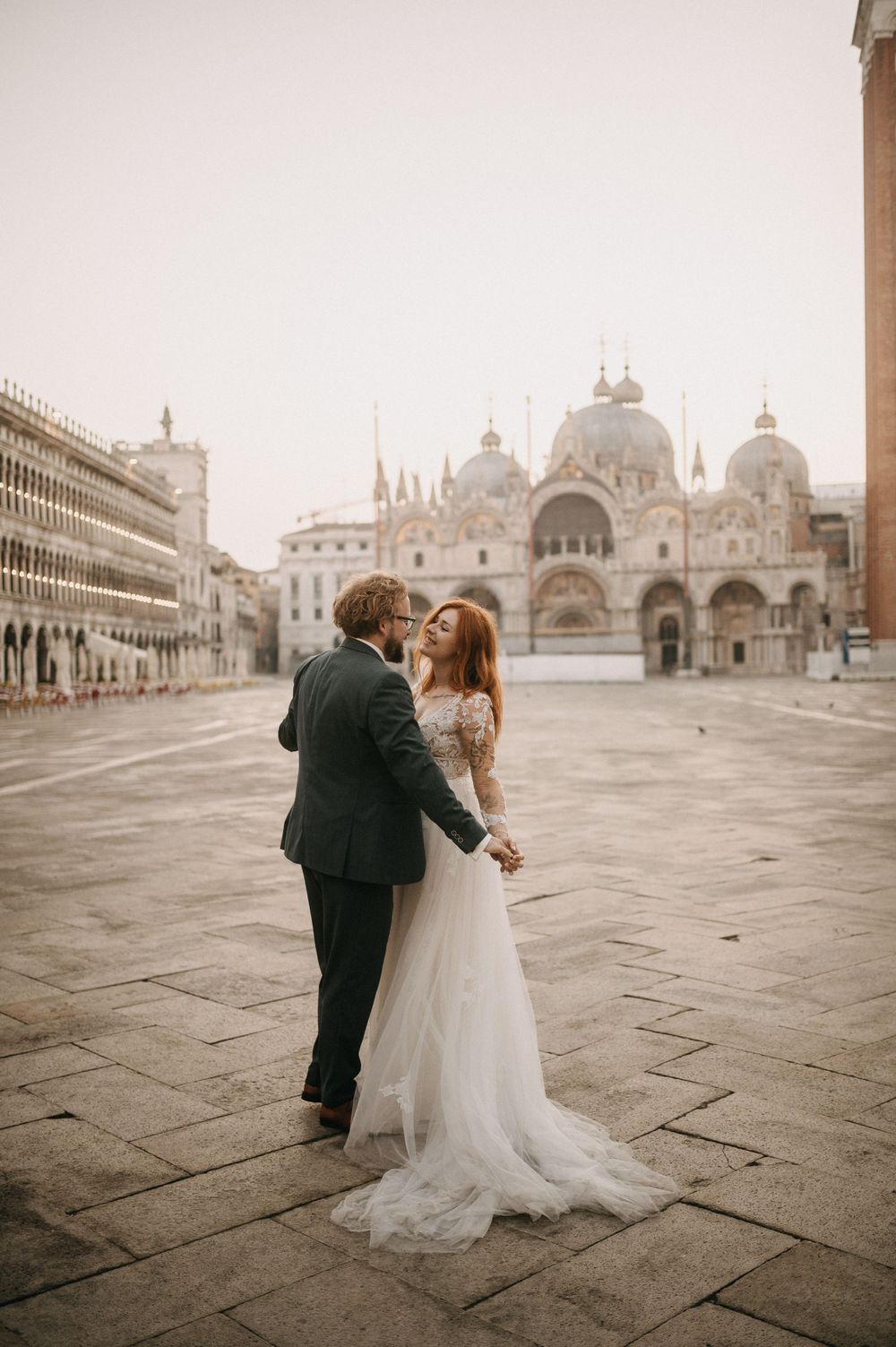 Romantic couple in wedding attire twirling on St. Mark's Square in Venice.