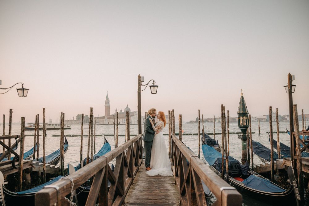 Moody wedding photo with gondolas lined up along Venice's misty waterfront.