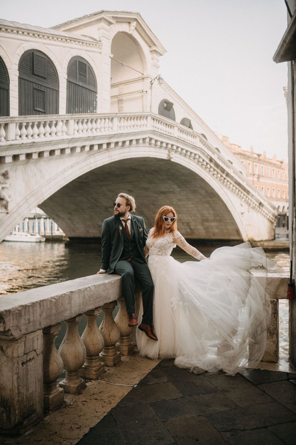A couple poses together under the arches of the Rialto Bridge in Venice, Italy.