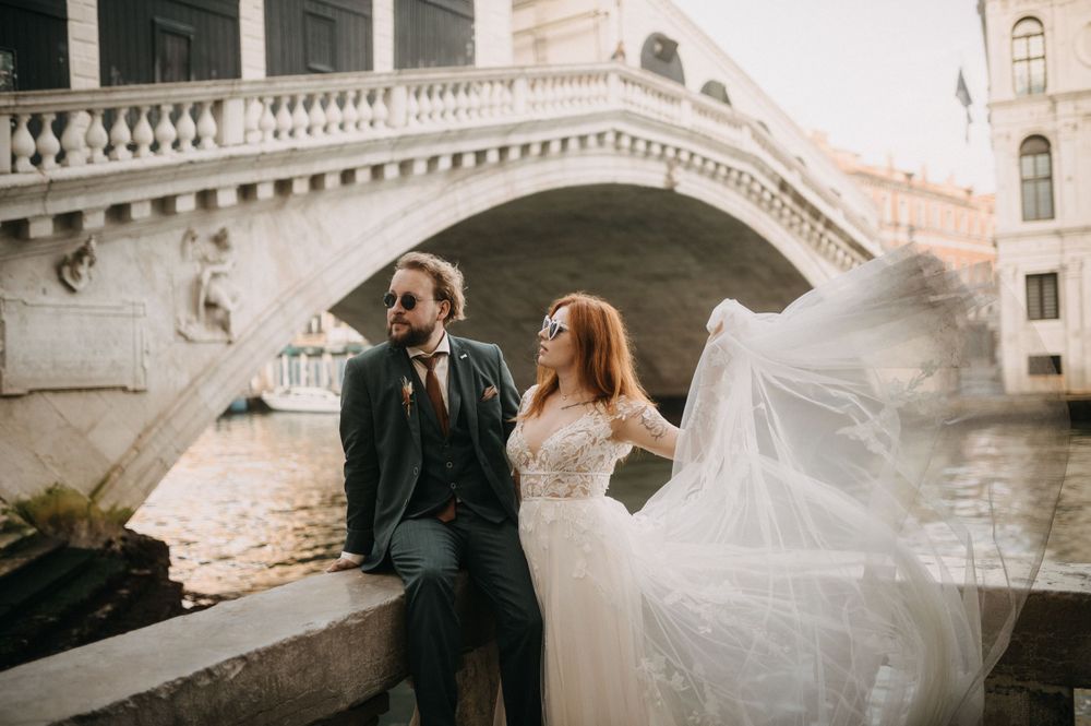 A romantic wedding photoshoot along a Venetian canal with historic architecture in the background.