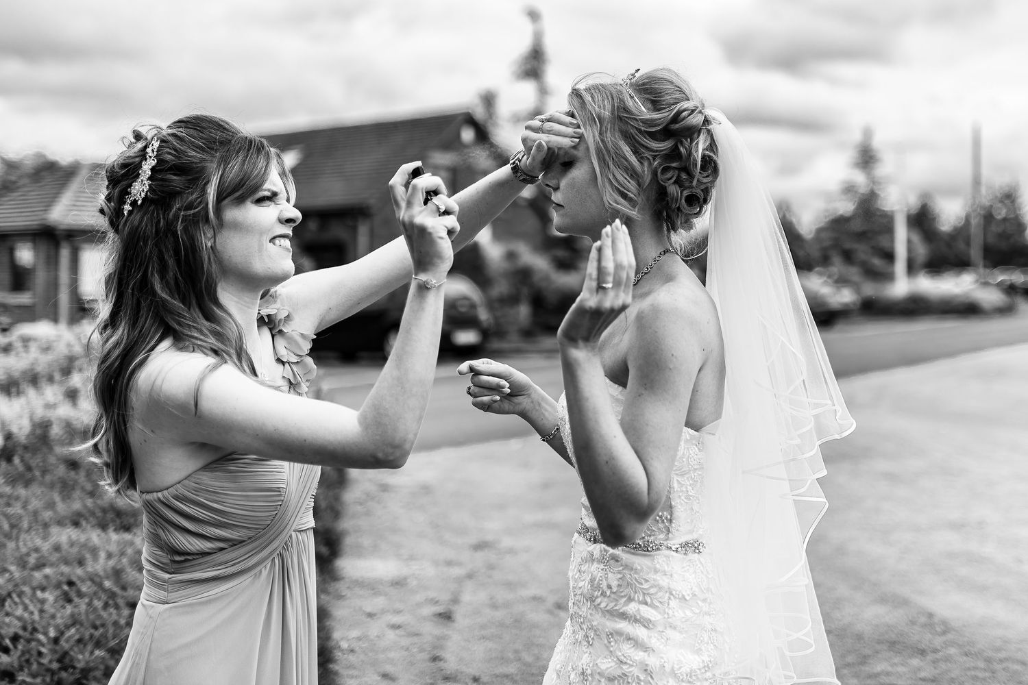 Bridesmaid gives the bride a quick spray of hairspray to hold her hair in place
