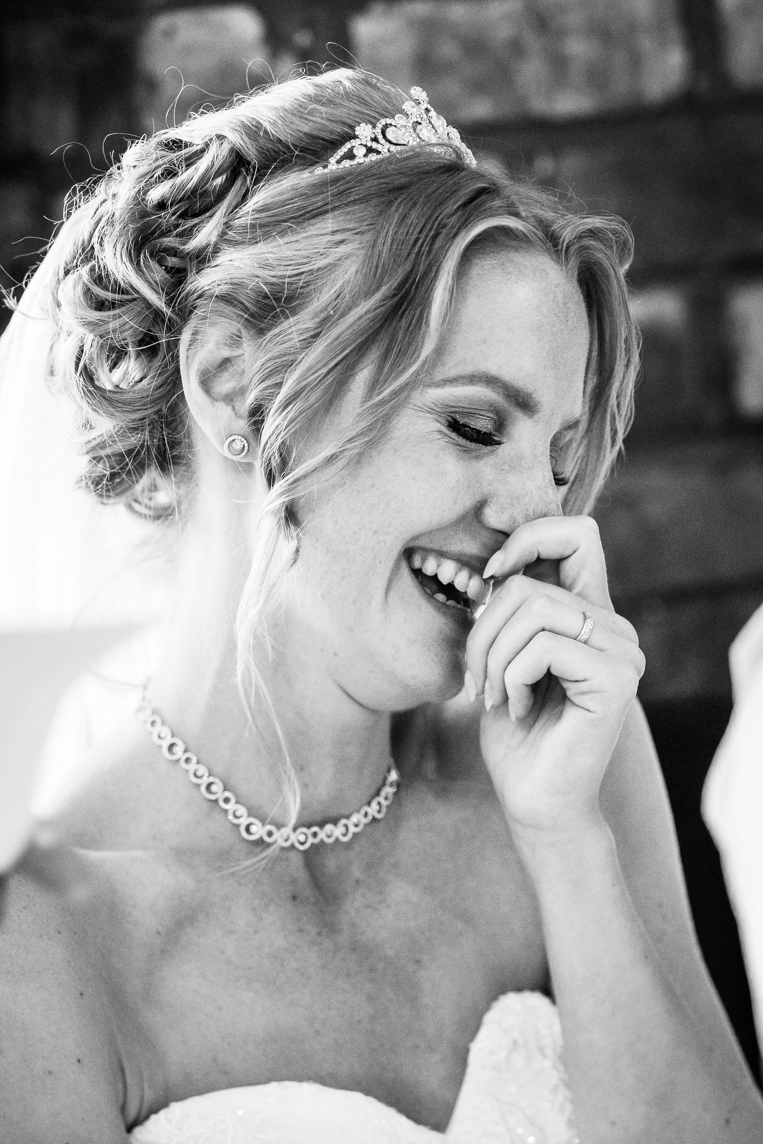 Bride smiling with her hand to her face during the wedding speeches