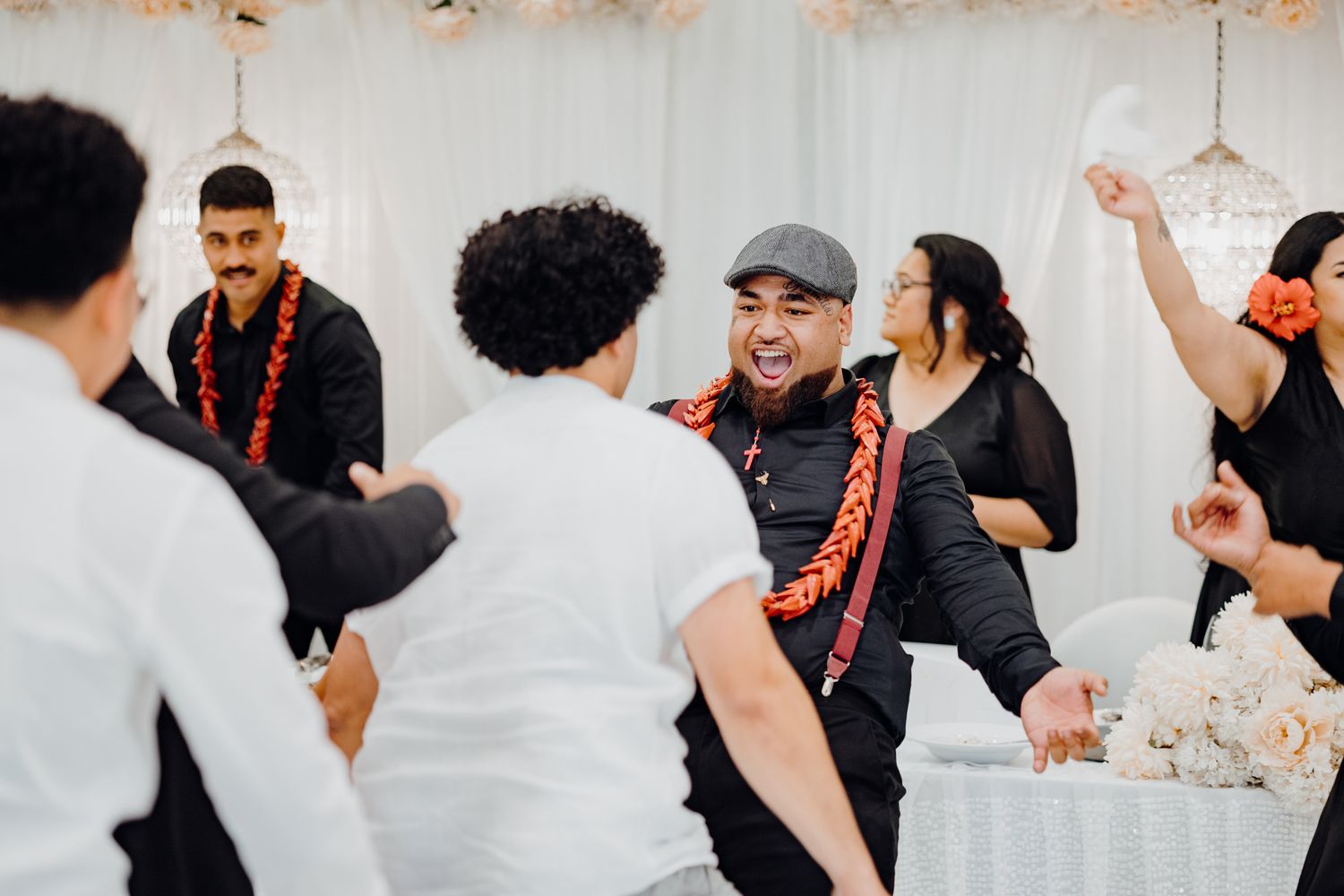 Wedding guests dancing and celebrating during a festive reception with white decor.