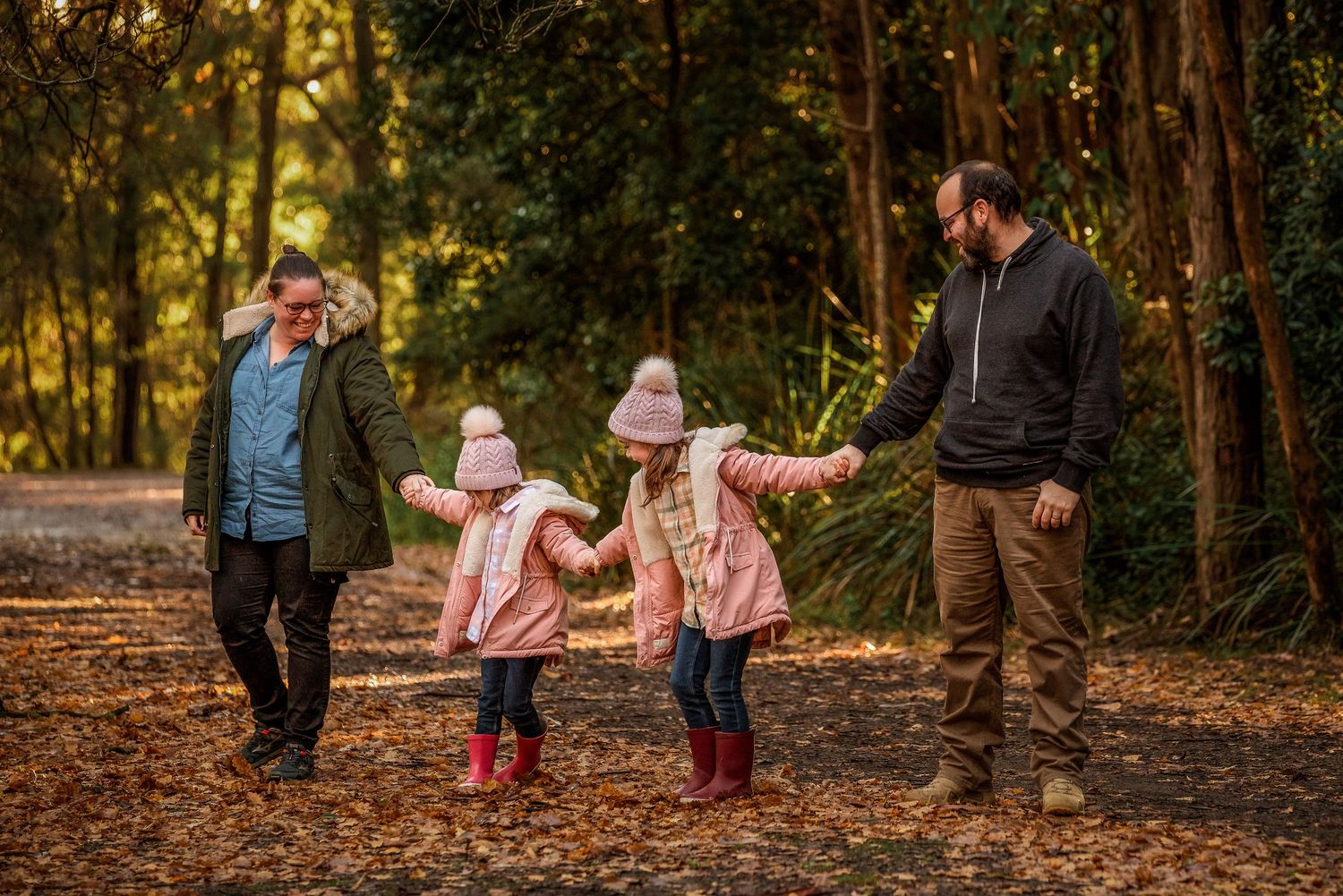 Family of four walking amongst the Autumn leaves by Kate Cashin Photography.