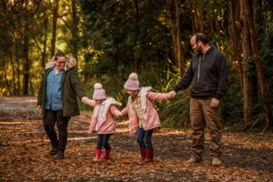Family of four walking amongst the Autumn leaves by Kate Cashin Photography.