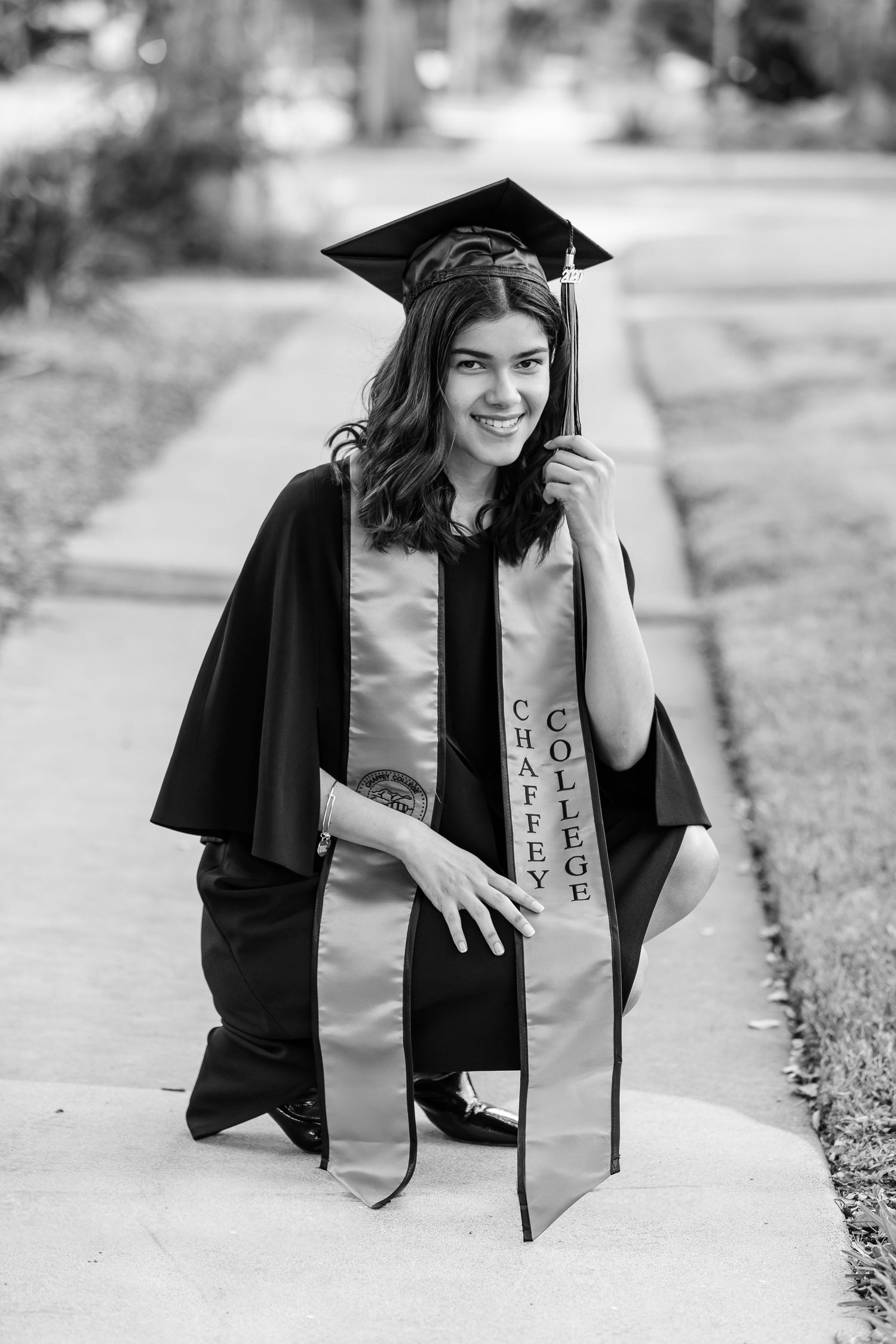 Girl crouching in her graduation sash, holding her tassel