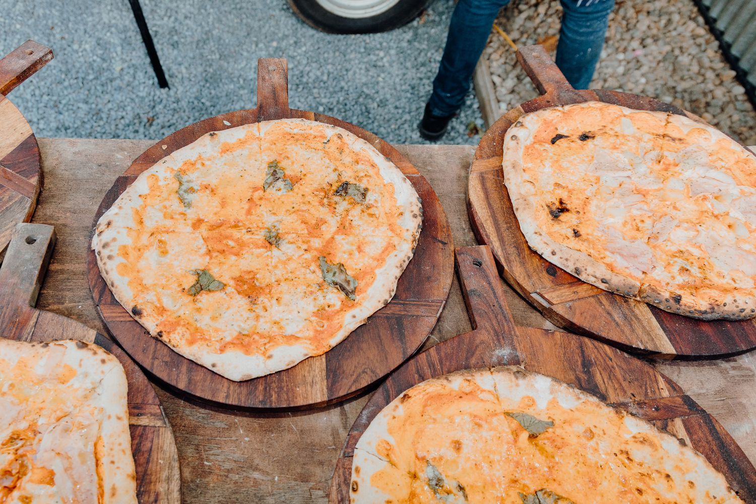 Fresh pizzas with melted cheese on wooden serving boards.