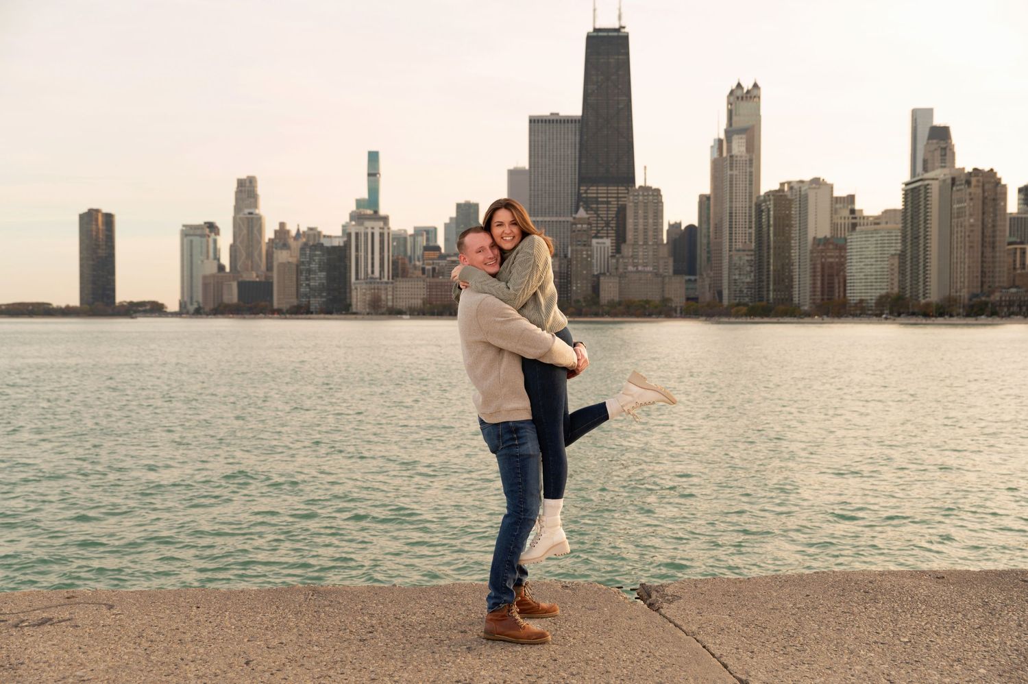 Couple embraces against Chicago skyline on Lake Michigan waterfront during sunset.