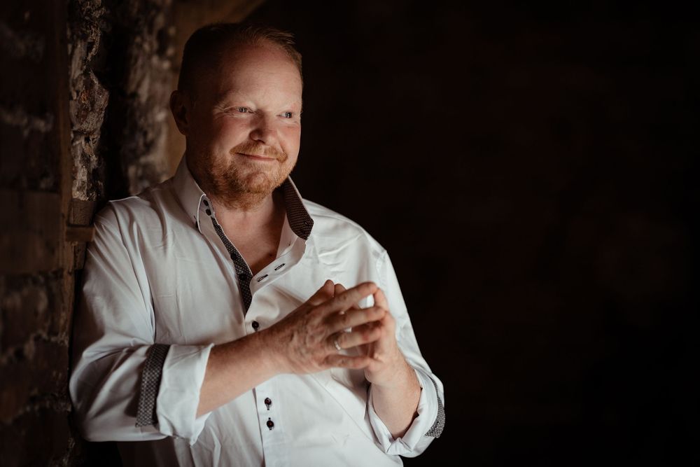 A collection of portrait images in low light with dramatic shadows against a dark background and white clothing.
