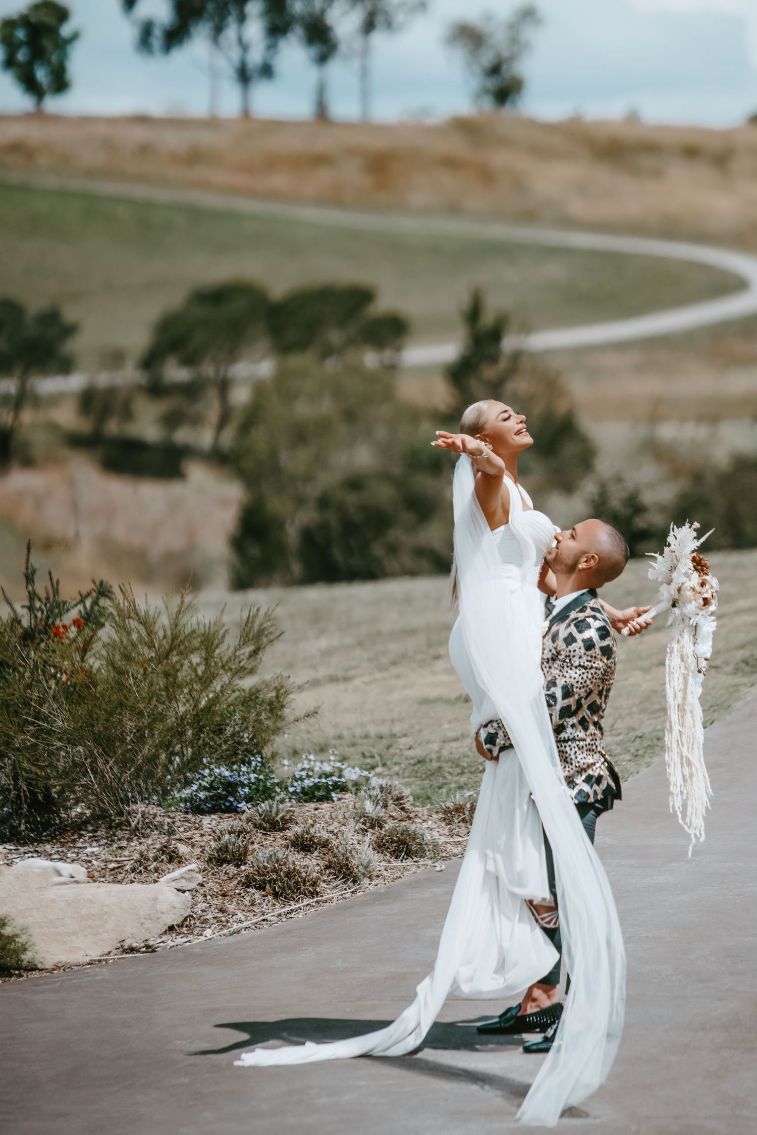 A celebratory wedding moment captured on a hilltop path with dramatic poses.