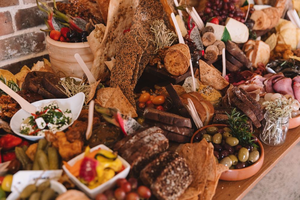Detailed view of artisanal meat and cheese board with fresh fruits and garnishes.