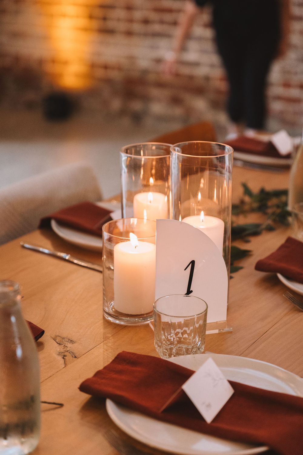 Elegant table setting with glowing candles in glass holders and burgundy napkins for table number one.