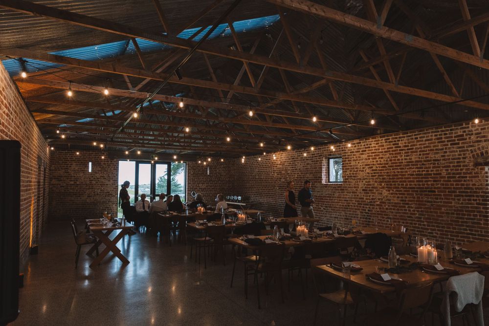 Industrial brick venue space with exposed beams and ambient lighting for wedding reception.