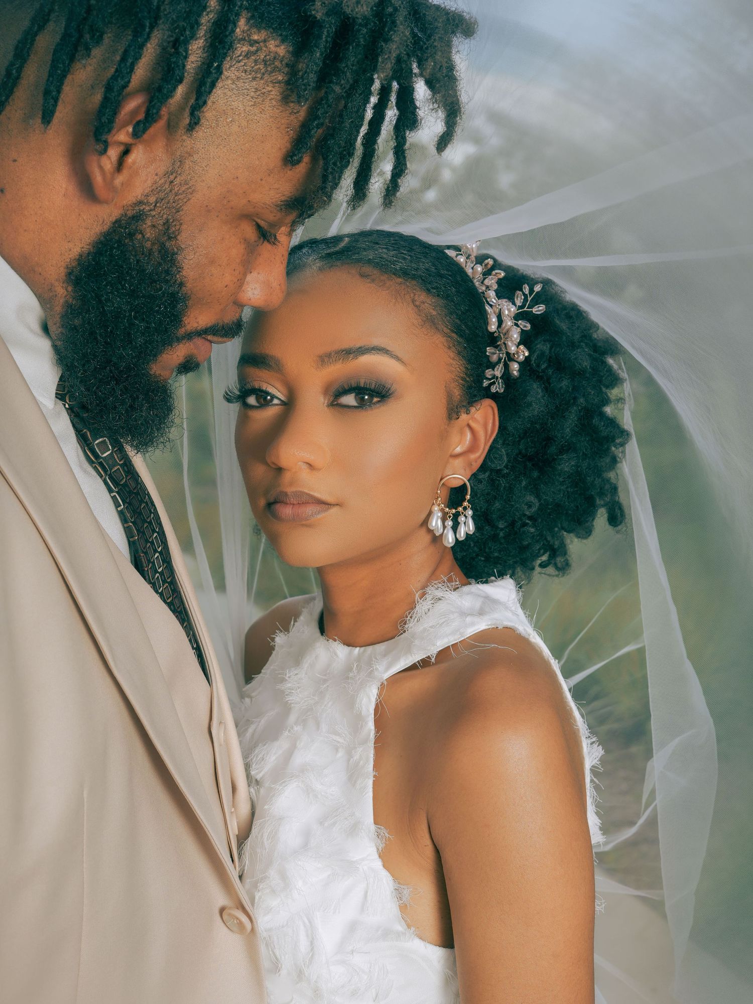 An intimate wedding portrait captures a couple under a delicate white veil.