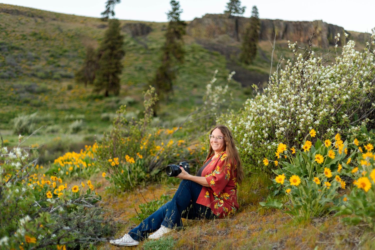wedding photographer and family photographer posing with her camera in a grassy field in Ellensburg, WA
