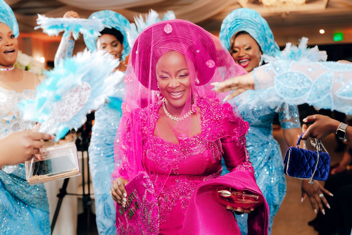 Traditional celebration with bright pink dress surrounded by guests in light blue attire during festive ceremony.