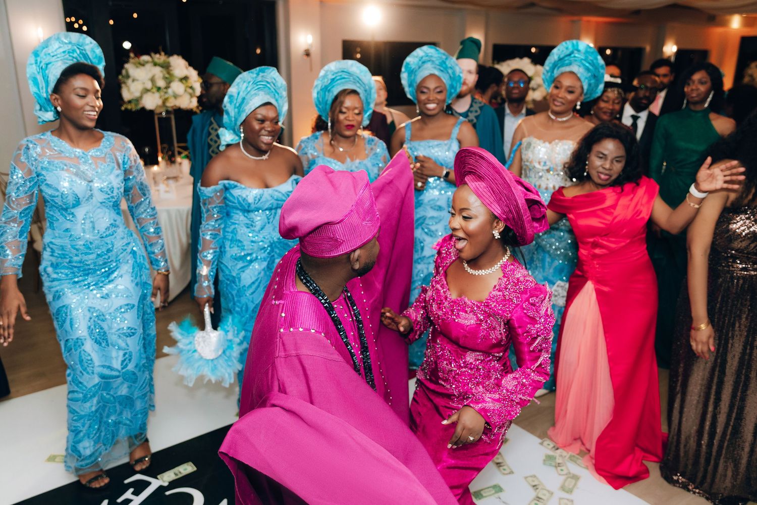 Wedding guests in vibrant blue and pink traditional outfits dance and celebrate during the reception.