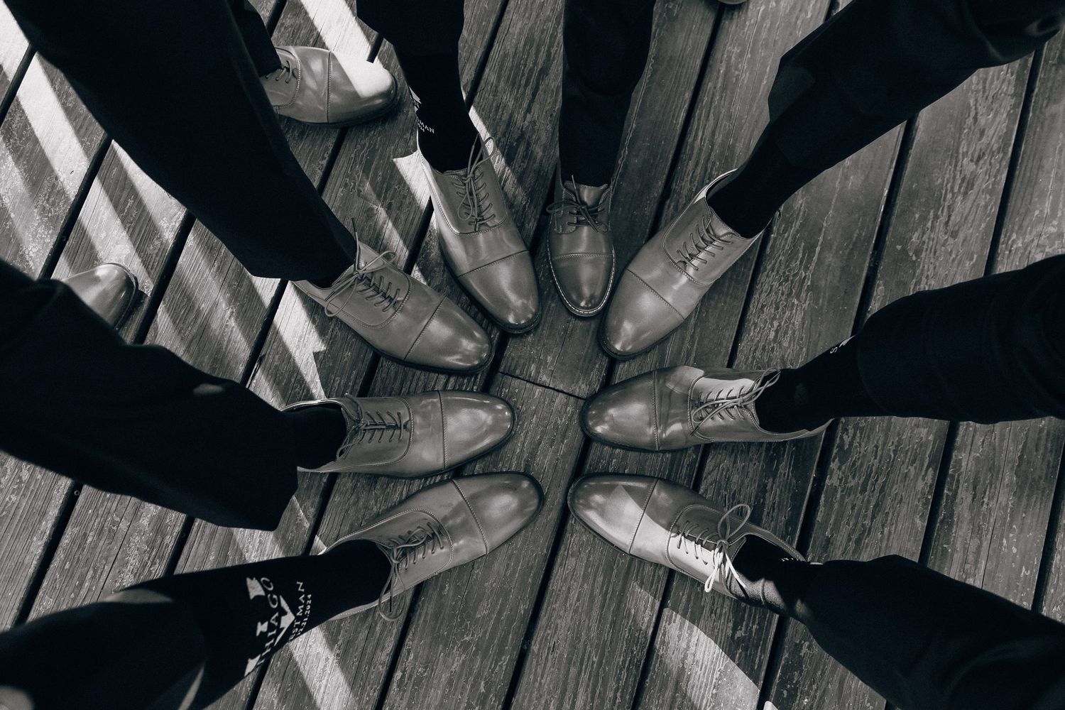 Artistic overhead view of dress shoes arranged in circle on wooden deck.