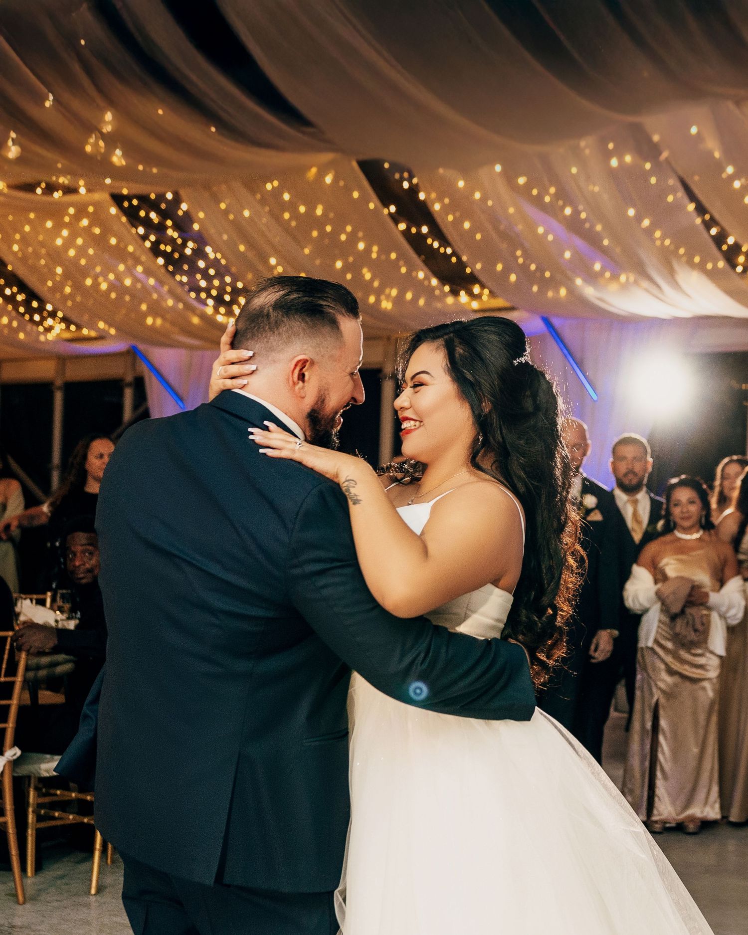 A romantic first dance under twinkling lights at an evening wedding reception.