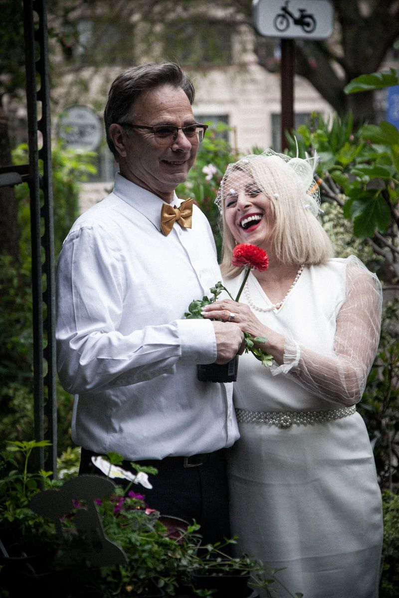 Couple in formal attire sharing joyful moment in garden setting.