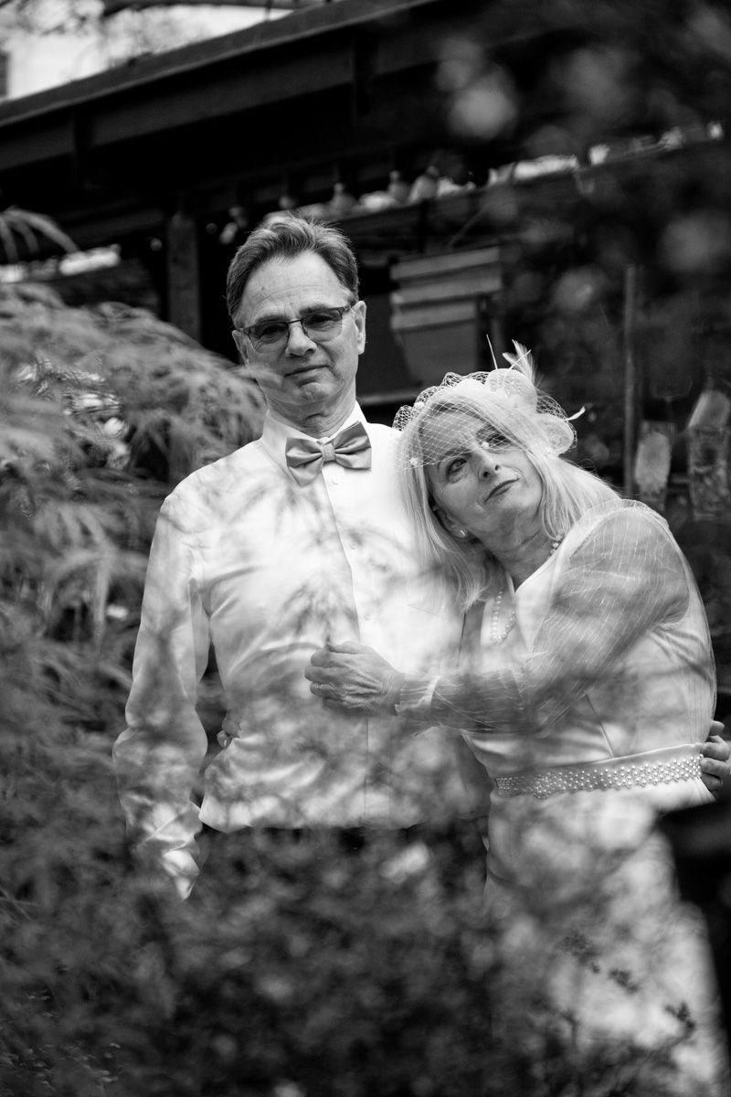 Romantic black and white portrait taken in a lush garden setting with soft bokeh effect.