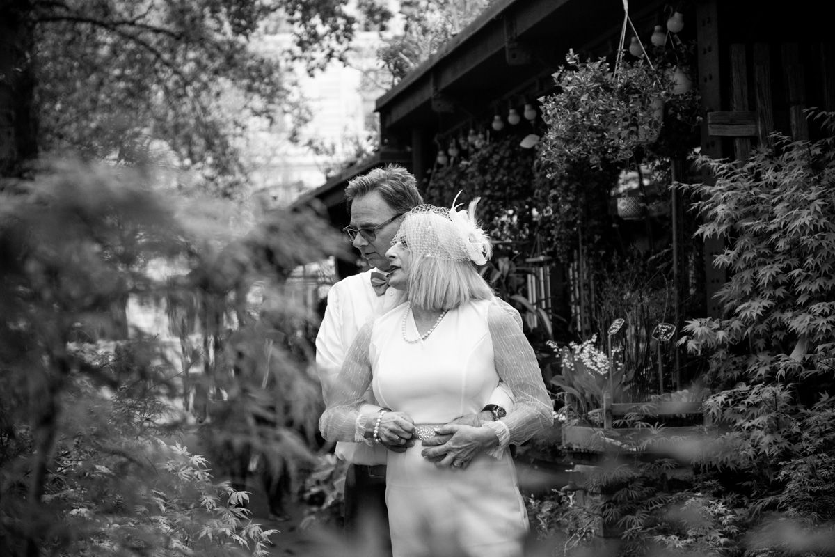 Intimate black and white garden photoshoot with soft natural lighting and foliage backdrop.