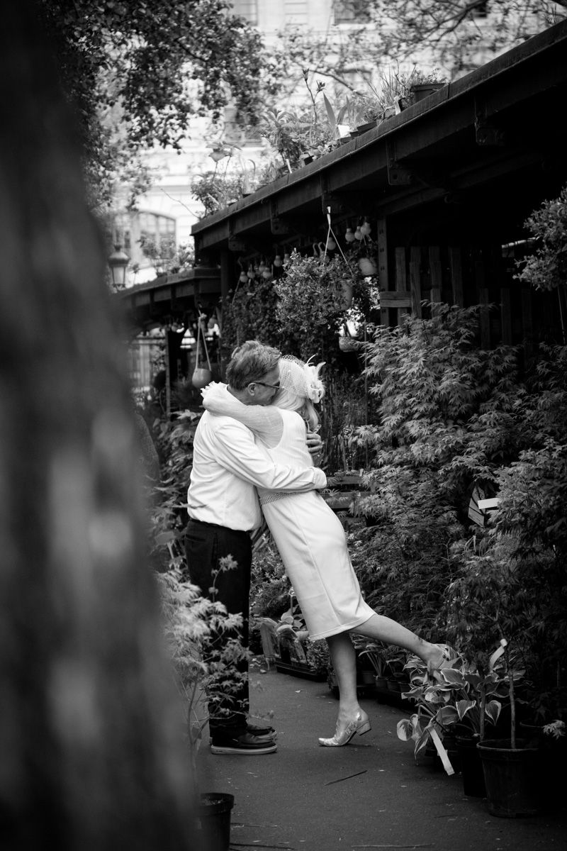 Joyful embrace captured in black and white among potted plants and greenery.