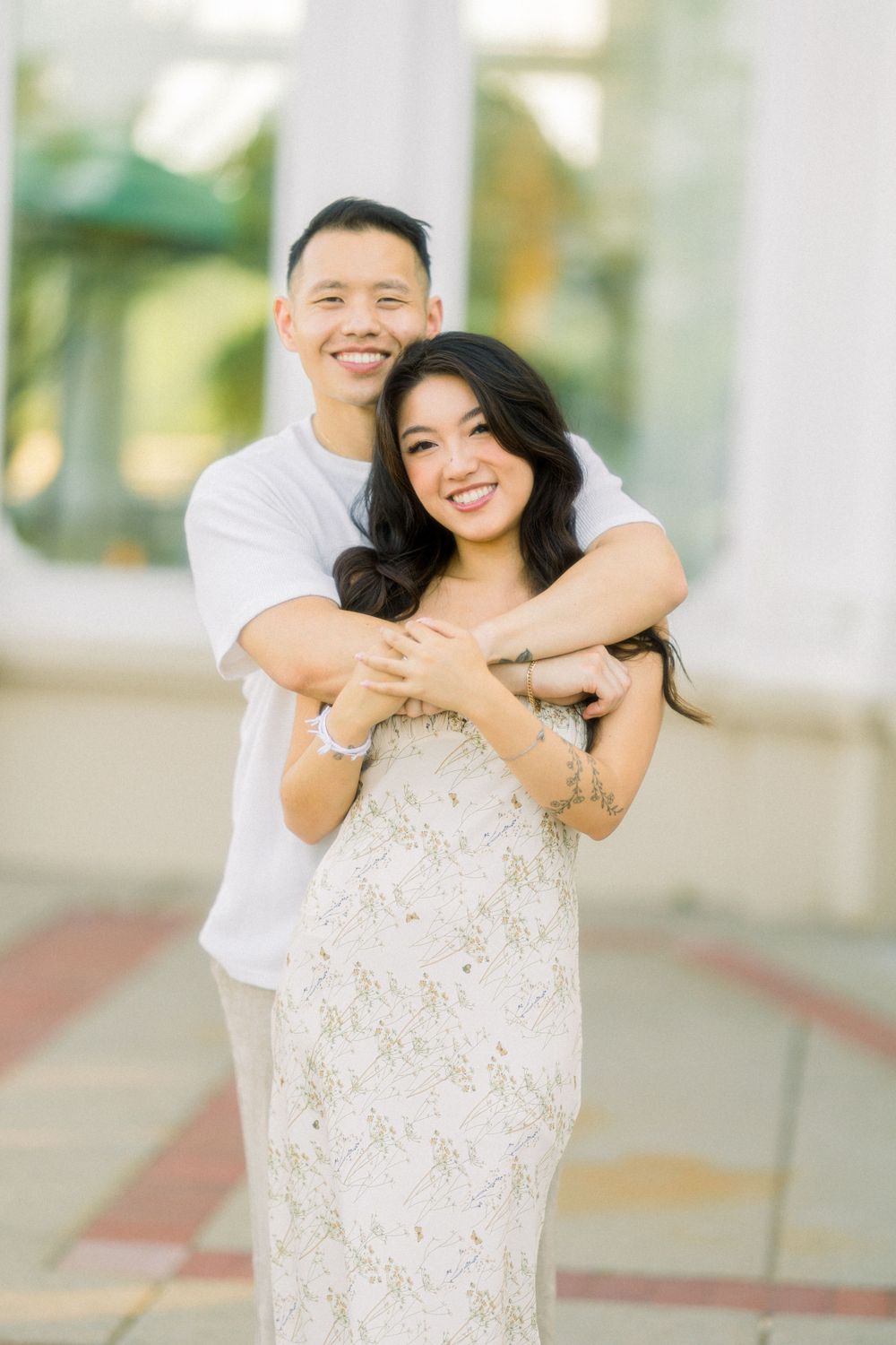 Happy couple embracing and smiling in front of white conservatory columns.