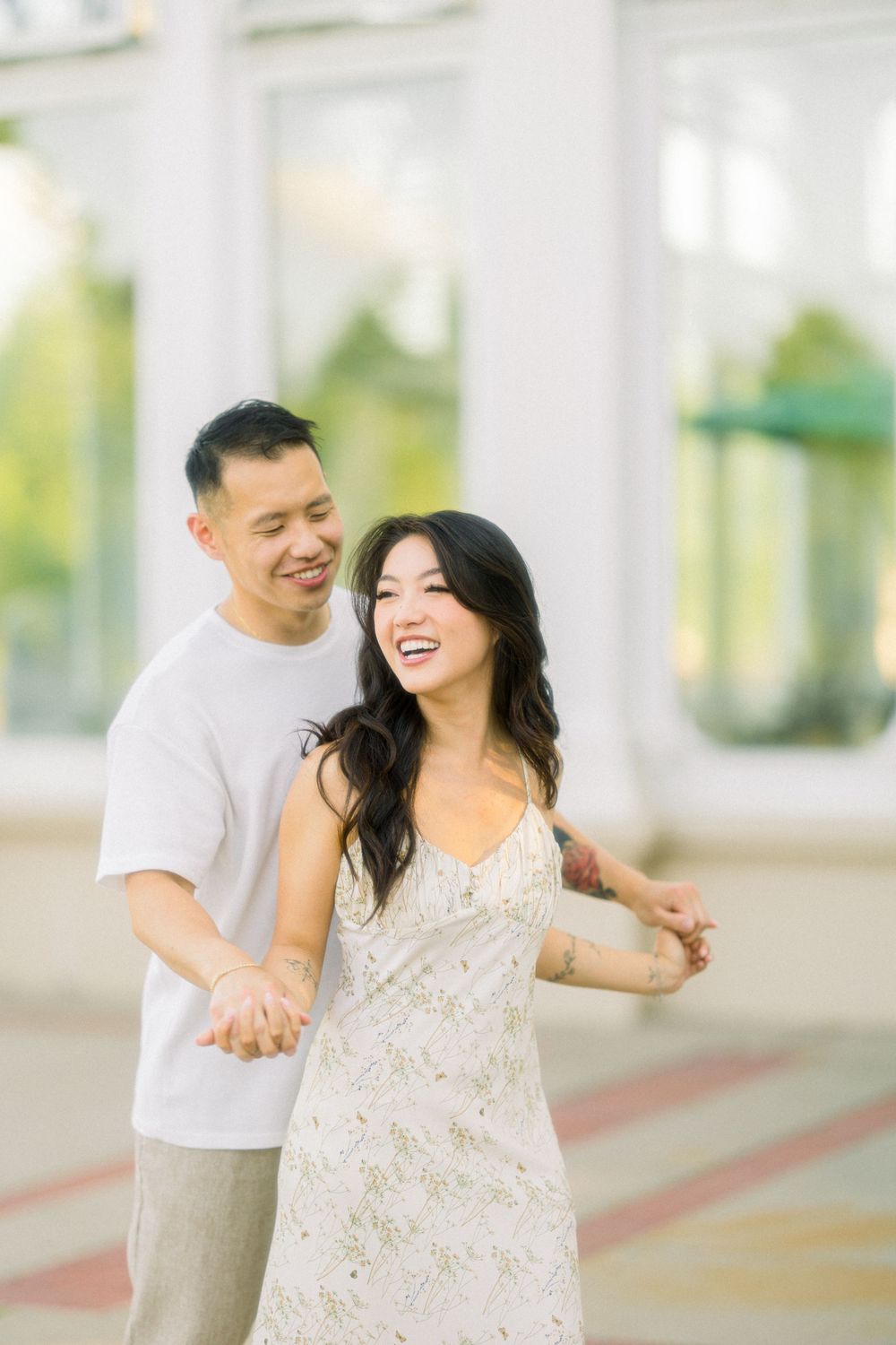 Dancing couple sharing laughter during engagement photo session.