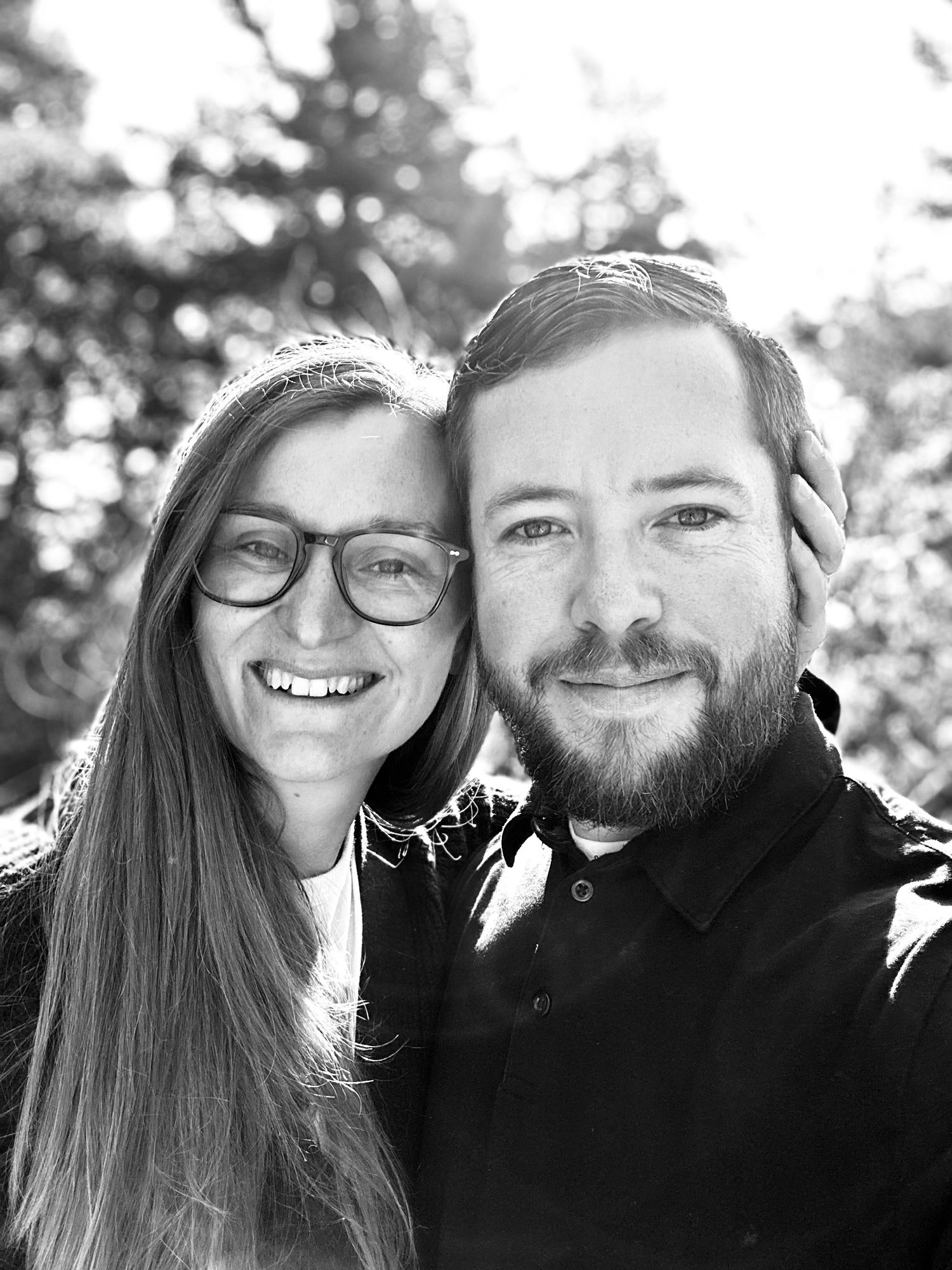 Close up portrait of couple smiling together outdoors in black and white.