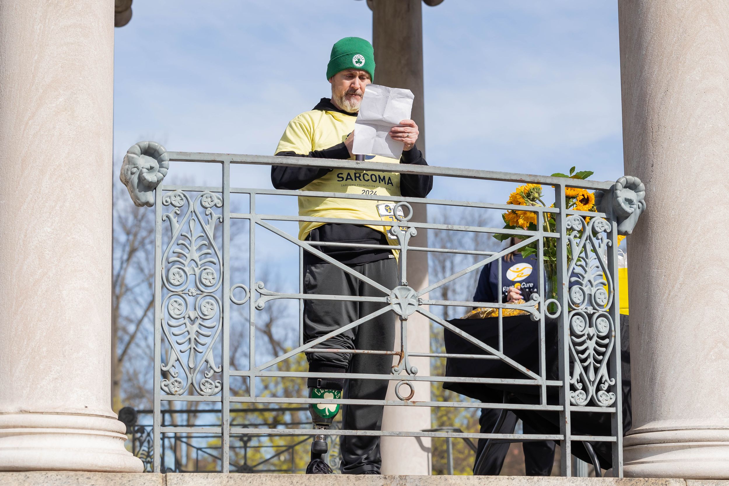 Person in casual wear taking photos from a white columned balcony.