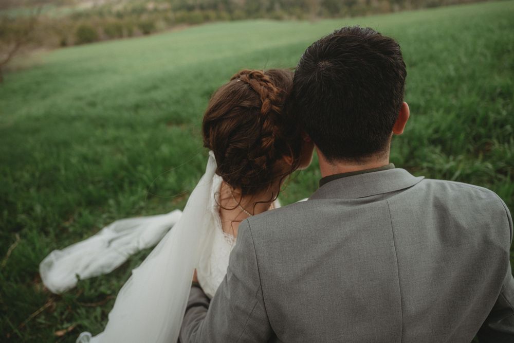 A wedding couple shares an intimate moment overlooking rolling green hills.