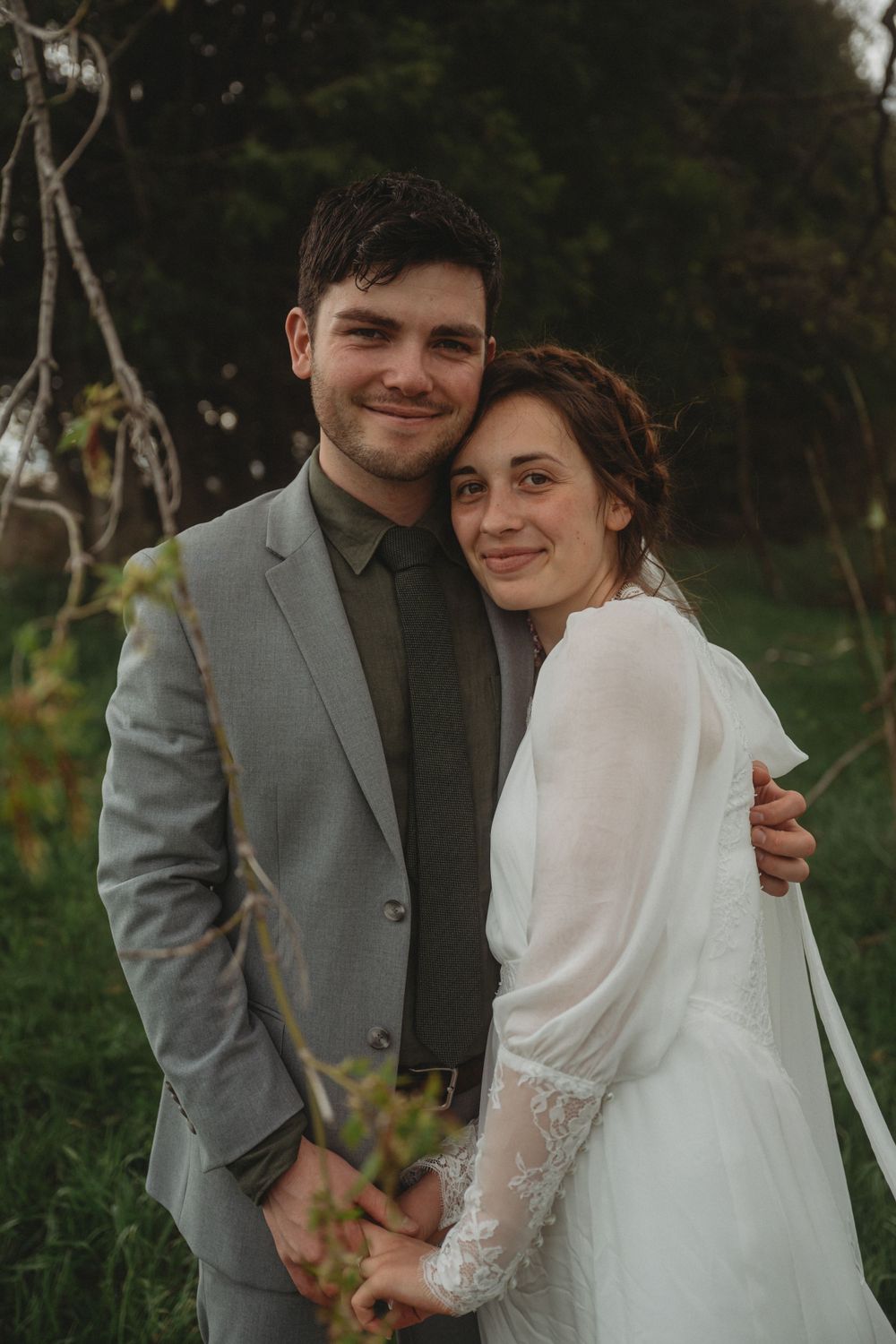 A romantic wedding portrait in a natural outdoor setting with greenery.