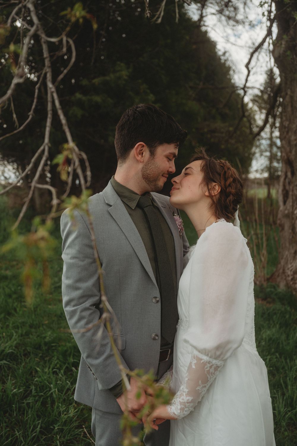A romantic moment between newlyweds surrounded by natural foliage.