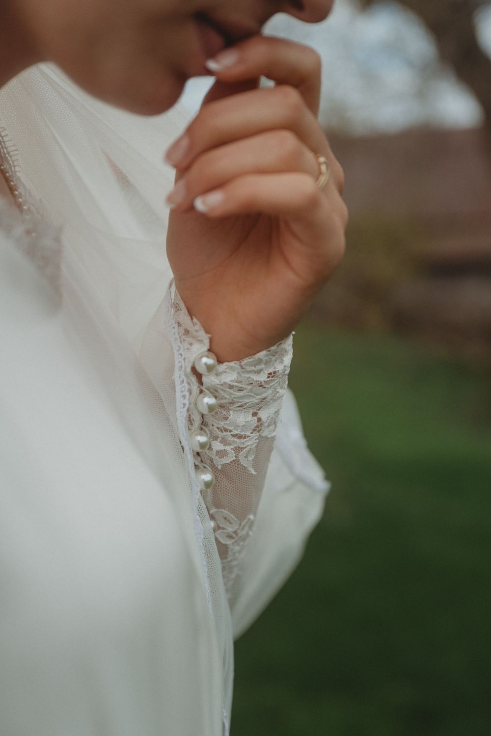 Close-up detail of delicate lace sleeve on a white wedding dress.