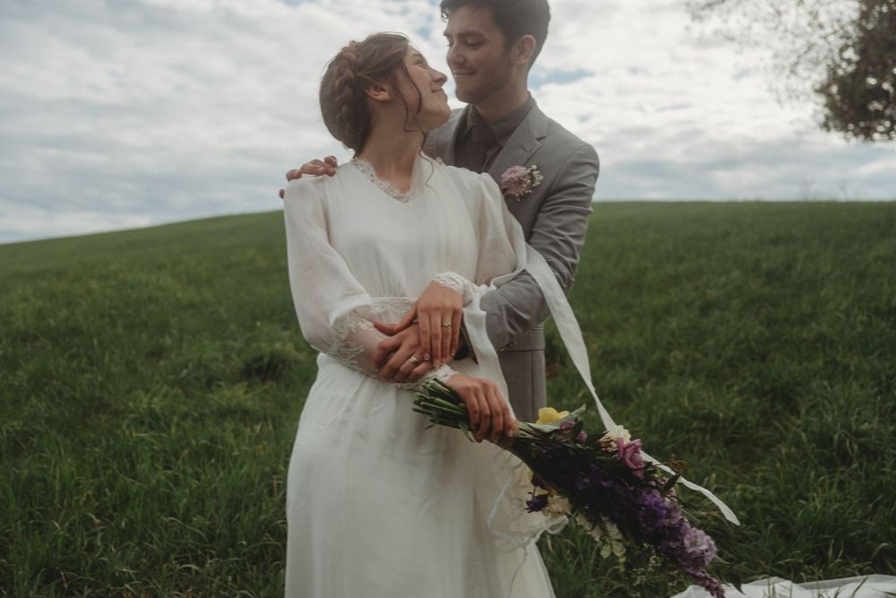 A romantic moment captured on a hilltop with flowing white dress and spring bouquet.
