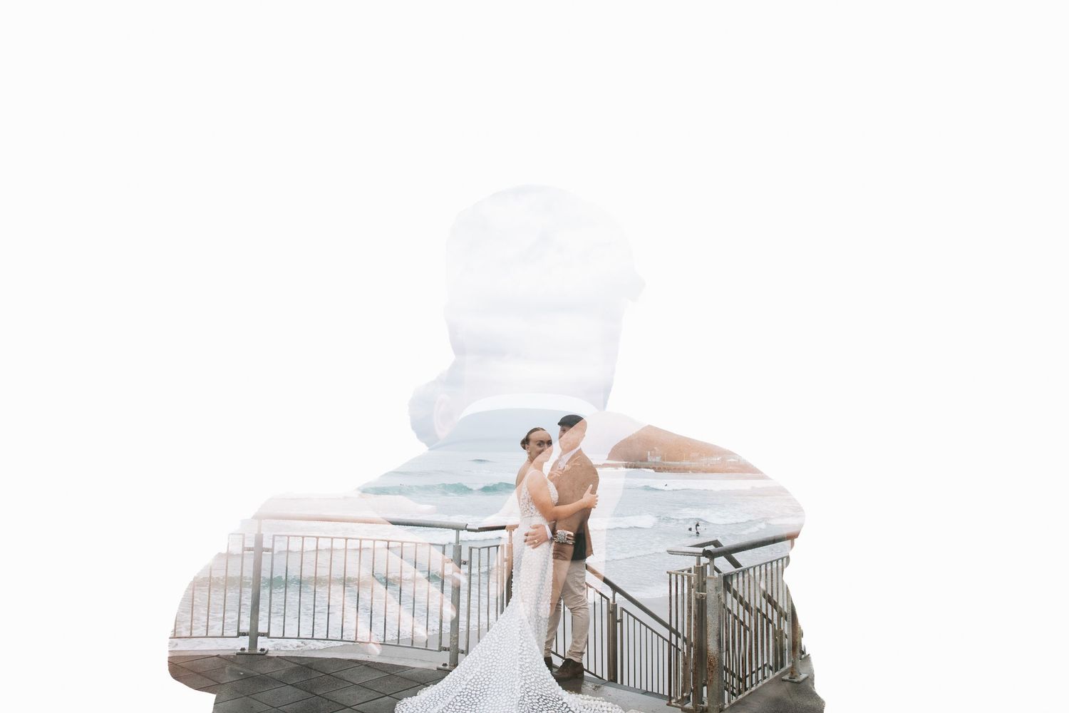 A wedding couple poses on a balcony with a creative double exposure silhouette effect against a cloudy sky.