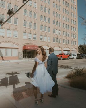 A couple shares a romantic dance in a sunset-lit parking lot outside an office building.