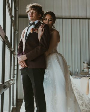Wedding party members in formal attire embrace and share intimate moments during celebration at an indoor venue.