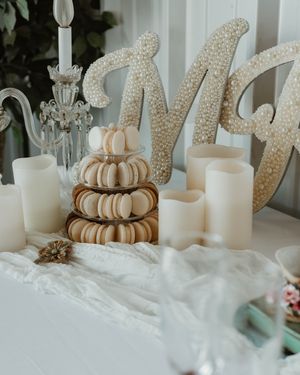 Wedding dessert table with stacked macarons, crystal candelabra, and glittery 'Mr' decorative letters.