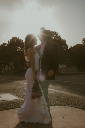 A tender silhouetted wedding couple embraces in the sunlight with trees in the background during golden hour.