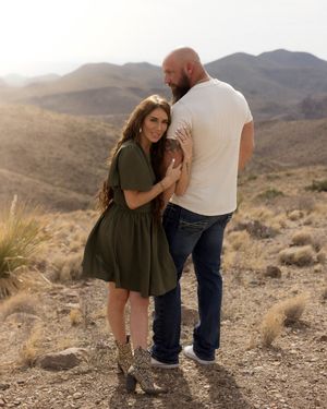 A romantic desert engagement photoshoot with mountains and desert brush in the background.