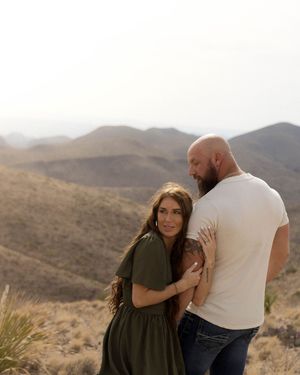Couple sharing an intimate moment in front of rocky desert mountains during golden hour.