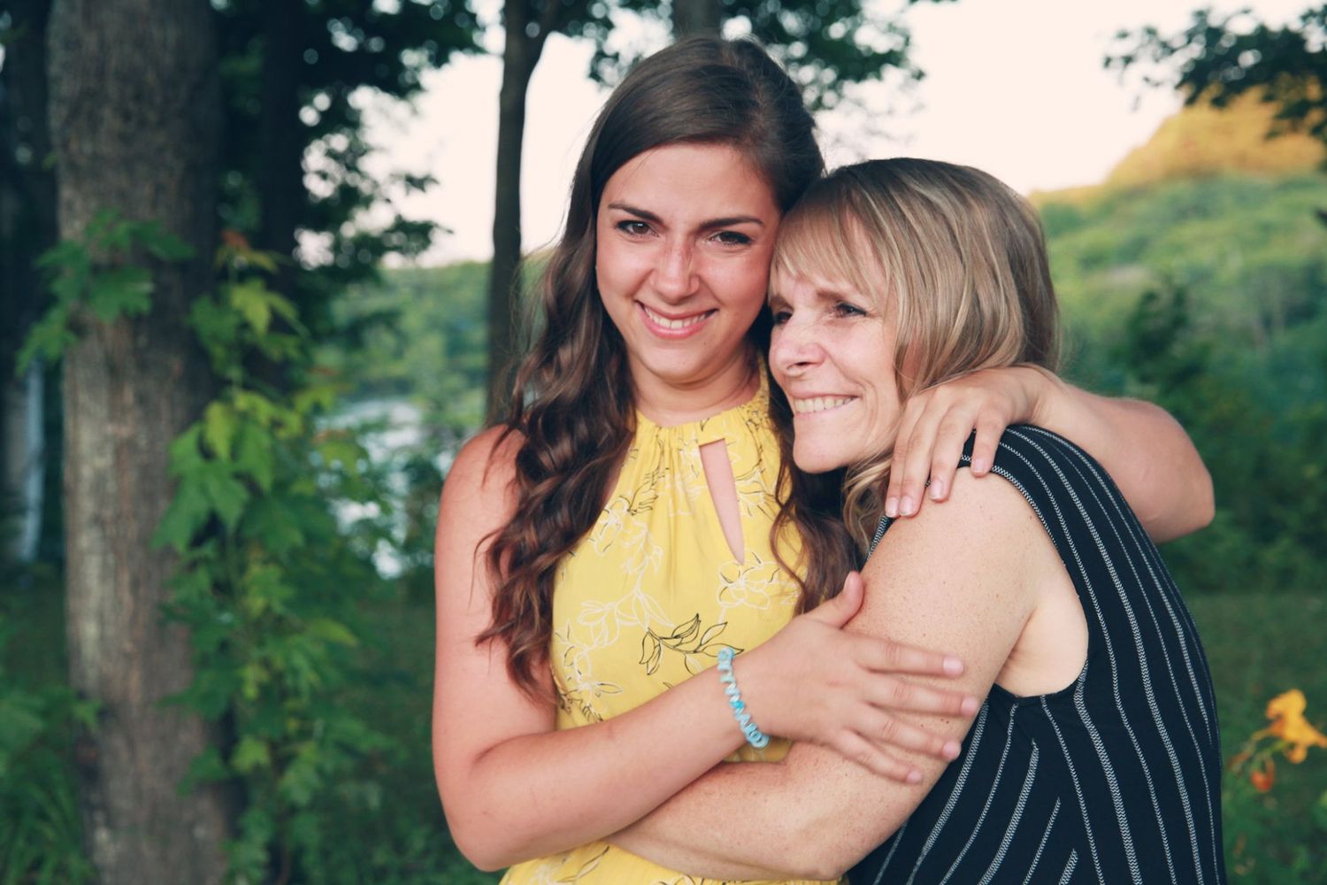 Friends share laughter while hugging during an outdoor summer photoshoot.